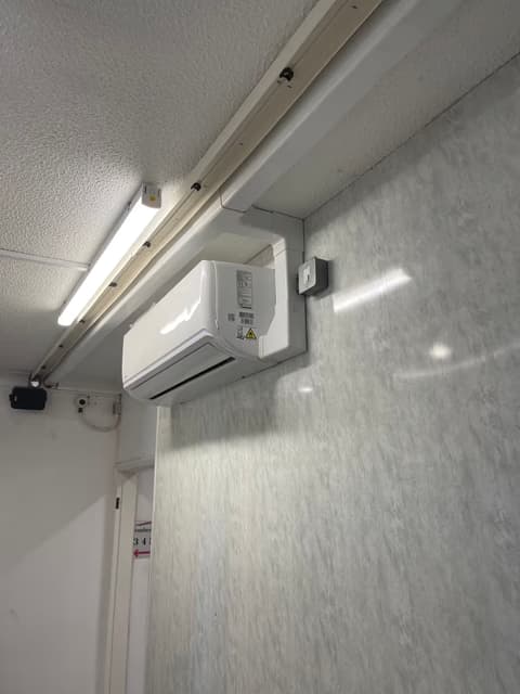 Wall-mounted air conditioning unit installed in a commercial office with fluorescent lighting