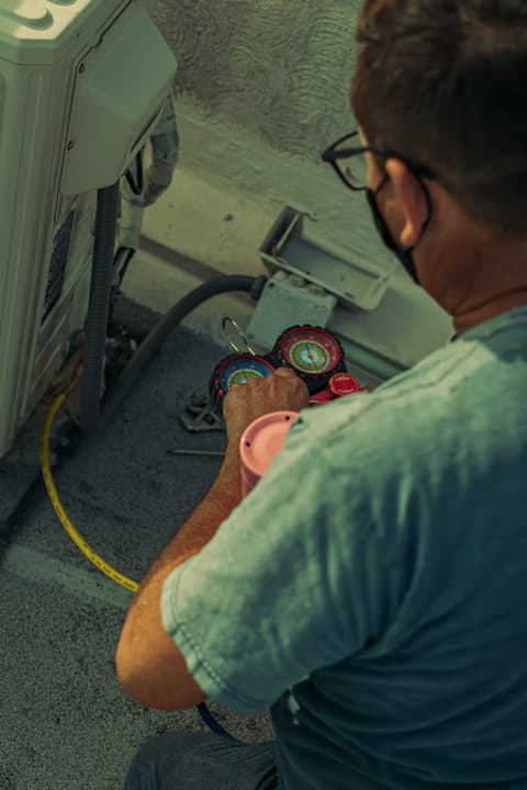 Engineer diagnosing an air conditioning fault with refrigerant pressure gauges
