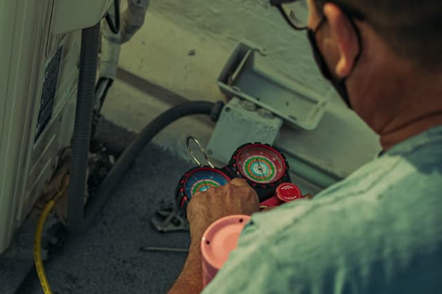 Air conditioning engineer checking refrigerant pressures with a manifold gauge during a service