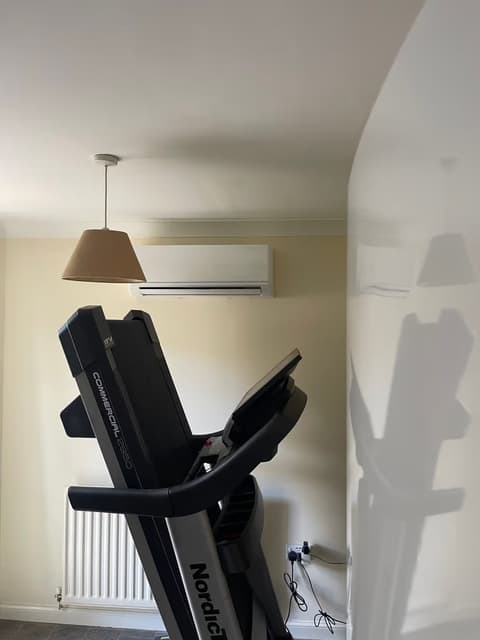 Wall-mounted air conditioner cooling a home gym with a treadmill