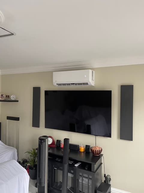 Air conditioning unit above a wall-mounted TV in a home cinema living room