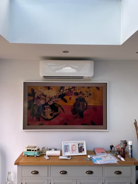 Newly installed wall-mounted air conditioning unit above artwork in a living room with a roof lantern