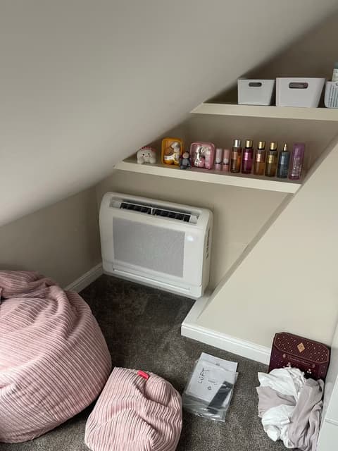 Floor console air conditioner in a loft conversion bedroom with a sloping ceiling