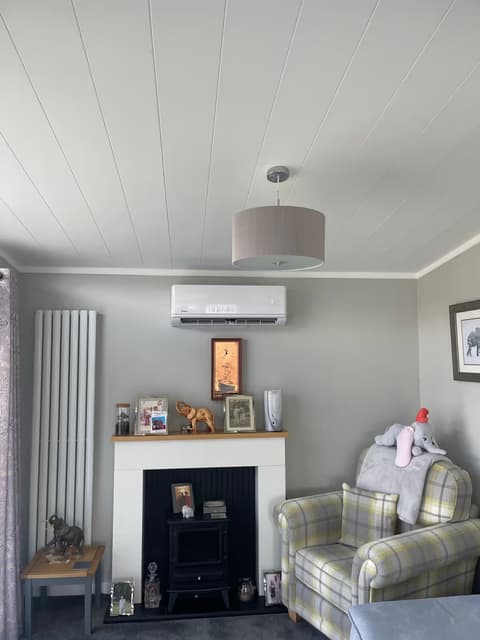 White wall-mounted air conditioner above the fireplace in a bright family lounge