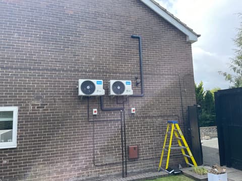 Two air conditioning outdoor units installed high on a gable wall