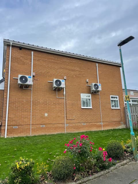 Row of commercial air conditioning condenser units mounted on the side of an office building