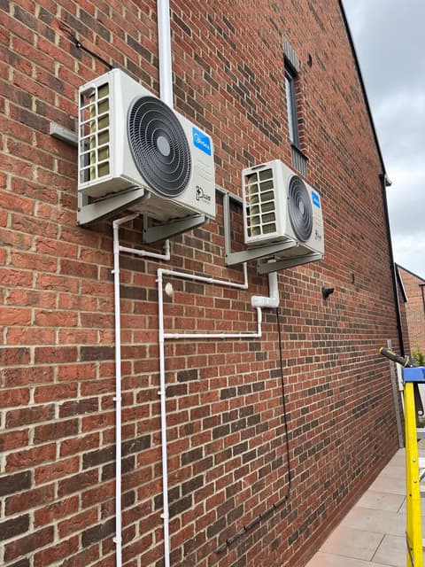 Two condenser units on wall brackets with neat white trunking