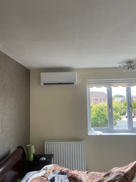 White wall-mounted air conditioner installed beside a window in a bright room