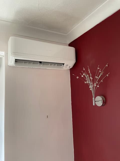 White wall-mounted air conditioner beside a red feature wall